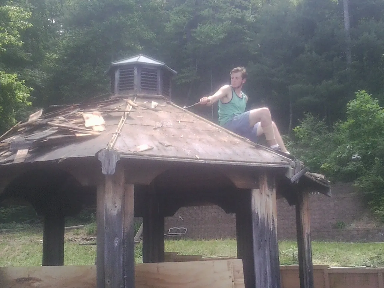Tearing the old roof off a wooden gazebo before new shakes in Laurel